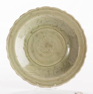 Longquan Celadon Scalloped Charger: Chinese Longquan celadon charger with central carved lotus blossom, carved scrolling foliate designs to the sides and scalloped rim. Underside with lobed body and burnt orange unglazed center. 10