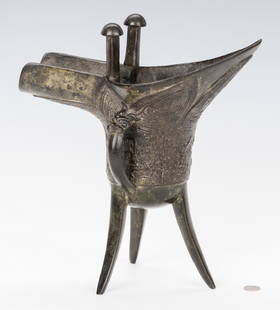 Chinese Archaic Bronze Jue: Chinese Archaic bronze ritual wine vessal or Jue, Shang Dynasty style, the body and underside with relief geometric decoration, two mushroom shaped finials, pouring handle and three splayed legs. 11