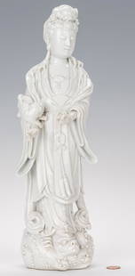 Blanc de Chine Porcelain Quan Yin Figure: Blanc de Chin porcelain Quan Yin figure, depicted standing with a foo dog in one arm, atop a wave base with foo dog fish. Impressed seal mark upper back. 14" H. 20th century. (Additional