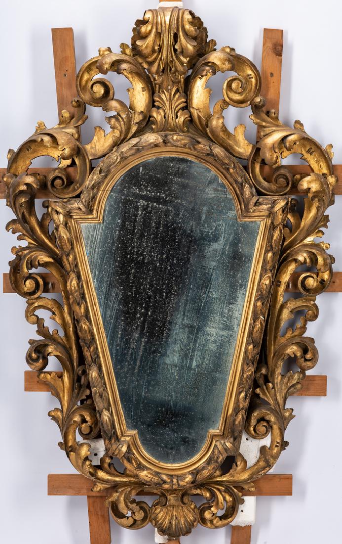 Continental Baroque Gilt Mirror: 19th century Continental or Italian shaped and carved gilt Baroque style mirror, ornately carved wooden frame surmounted by a scrolled ancanthus leaf finial with foliate carved sides and carved shell 