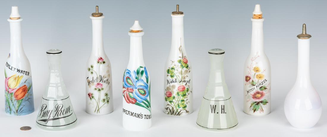 6 Milk Glass & 2 Moonstone Clambroth Barber Bottles, 8: Group of eight (8) early 20th century barber bottles including five (5) floral decorated and labeled milk glass examples with stoppers (Toilet Water/Witch Hazel & Opperman's Tonic), one (1) plain milk
