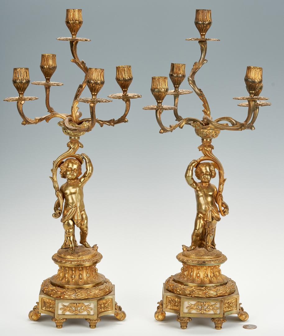 Pair Ormolu Candelabra with Cherubs: Pair of gilt bronze 5-light candleabra, each candle arm issuing from a central branch, held by a cherub or putti standing on a circular, Neoclassical plinth base encircled with laurel leaf wreath, ato