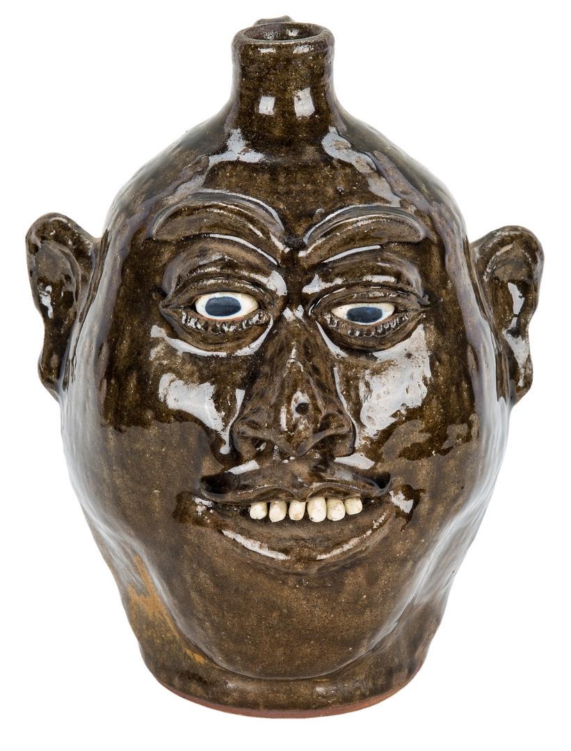 Lanier Meaders Folk Art Pottery Face Jug: Lanier Meaders (White County, Georgia, 1917-1998) folk art pottery face jug having a green alkaline glaze with porcelain eyes and teeth. Incised signature on the base. 9 3/4" H. 20th century. Provenan
