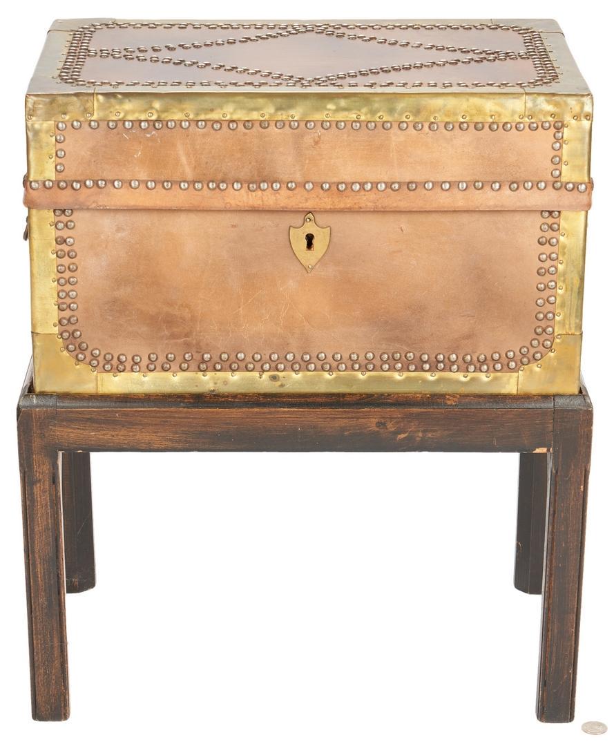 Brass Mounted Box on Custom Stand: Leather covered walnut document box with hinged cover, brass bound edges and decorative brass tack ornamentation, shield shaped escutcheon and brass key, brass bail side handles, fitted into a custom 