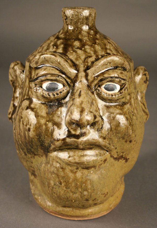 Lanier Meaders folk pottery face jug: Lanier Meaders (White County, GA, 1917-1998) face jug. Green alkaline glaze drips, blue cobalt eyes. Signed in script on the bottom, "Lanier Meaders". Excellent condition. 9 3/8" height.