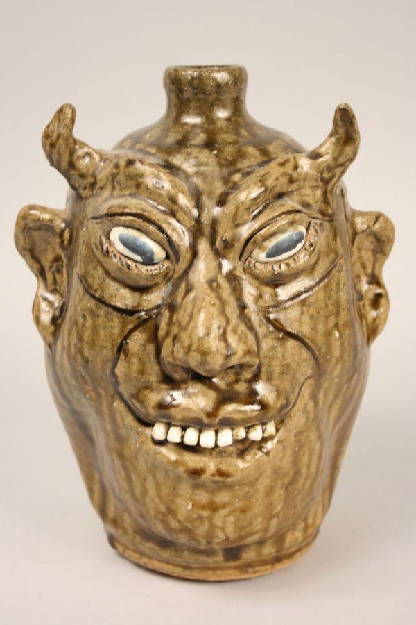 Lanier Meaders devil face jug: Lanier Meaders (White County Georgia, 1917-1998) devil face jug. Horned devil face with bulging eyes & ceramic teeth. Olive green alkaline glazed. Inscribed on bottom "Lanier Meaders". Overall excelle