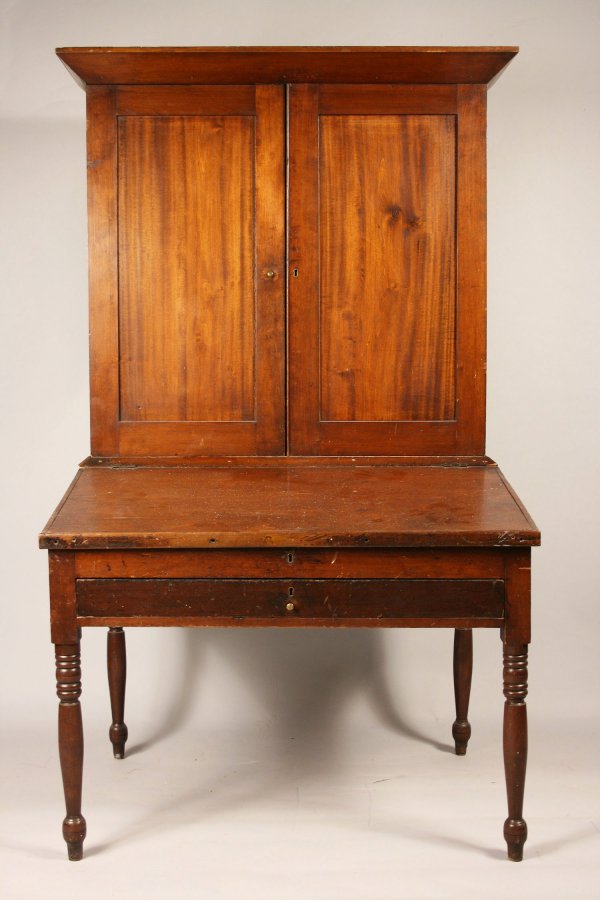Cherry plantation desk: Cherry plantation desk in the Sheraton style, old surface. Two piece with canted cornice over two doors over slant front desk with interior tills. Writing in interior of desk with inscription "Wyoming