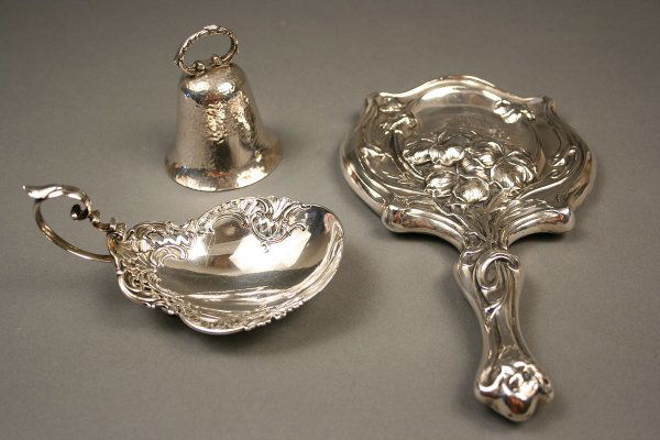 Three pcs. sterling silver decorative hollowware: Three pieces sterling silver decorative hollowware. 1st item - Art Nouveau hand mirror with lily design (9 1/4", polish wear, small dents, scratches to glass, monogrammed). 2nd item - Pierced handled