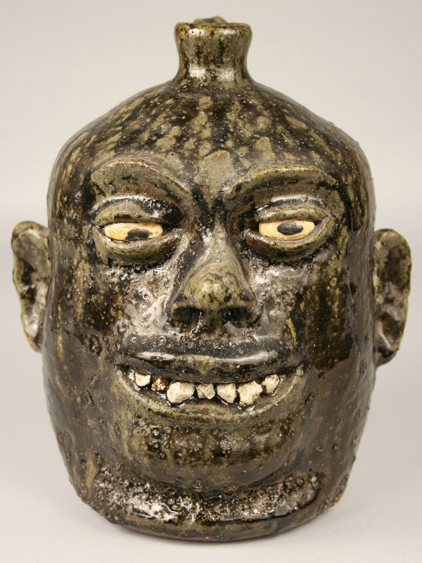 Lanier Meaders rock tooth face jug: Lanier Meaders early rock teeth face jug with painted eyes and runny dark olive glaze. Inscribed "Lanier Meaders" on base. Overall excellent condition. Measures 9 3/4" H.