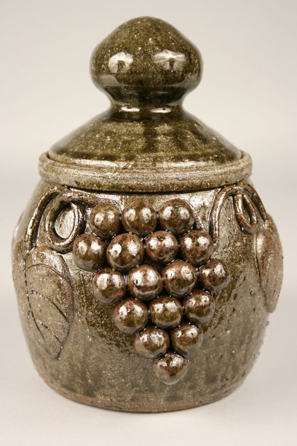 Edwin Meaders grape cluster jar with lid: Georgia Folk Pottery jar with domed lid by Edwin Meaders, decorated w/double cluster of grapes and leaves in high relief and dark alkaline green to brownish green glaze, incised on base in script "Edw