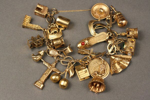 Yellow Gold Charm Bracelet, over 20 gold charms: Ladies yellow gold charm bracelet with 26 charms attached with marked 10K gold links and including 18K jeweled box, 14K movable ferris wheel, 12K movable windmill, 14K Viking ship, 18K ladies slipper,