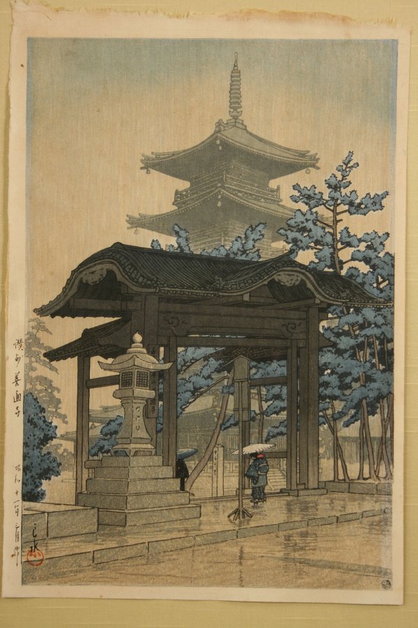 Japanese woodblock print, Hasui Kawase: Japanese woodblock print of a pagoda and blooming tree in background and figures with umbrellas in the foreground, by Hasui Kawase (1883-1957). Signed vertically in left margin and stamped in both low