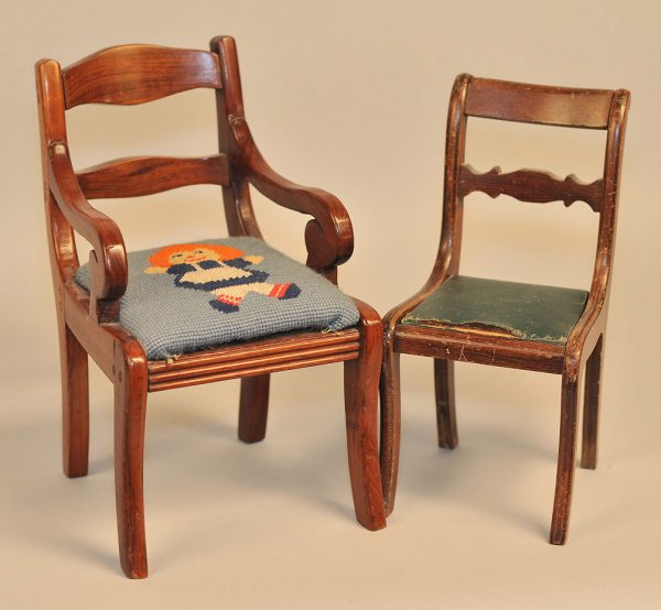 Two doll chairs, Grand Rapids label on one: Lot of two miniature Duncan Phyfe style chairs, salesman sample or doll chairs, mahogany with upholstered seats. Armchair has needlepoint seat depicting Raggedy Ann. Side chair has partial paper label