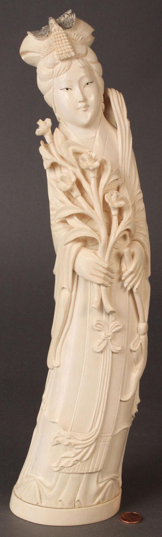 Carved Ivory Figure from an elephant tusk: Asian carved ivory figure from an elephant tusk of a woman holding flowers and brush, markings on base. Overall good condition with 2 small cracks at base of carving. 16 1/2" H. Chinese, mid 20th cent