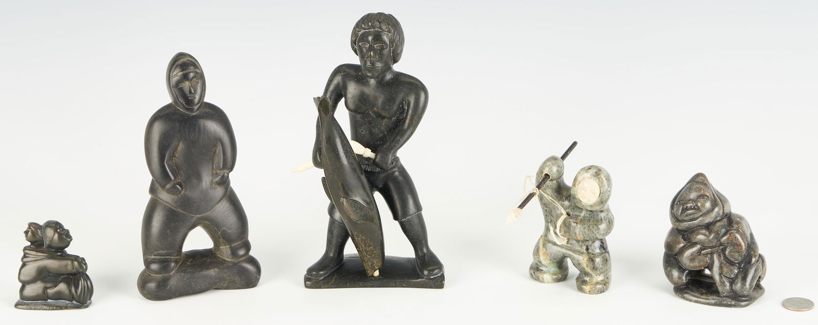 Five (5) Native American Inuit Carved Figures incl.: Five (5) Inuit carved soapstone figures, including one (1) Novoalia Alariaq (Cape Dorset, b. 1956) black soapstone carving depicting a fisherman figure with shorts in a wide stance holding a spearhead
