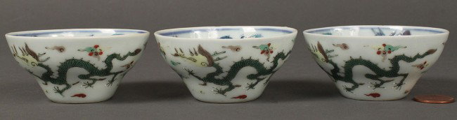 Lot of 3 Chinese Wucai Wine Cups: Lot of three Chinese Wucai eggshell porcelain wine cups depicting dragons chasing the flaming pearl of wisdom. Blue Yongzheng mark on underside. Excellent condition. 1 1/4" H x 2 3/4" dia.