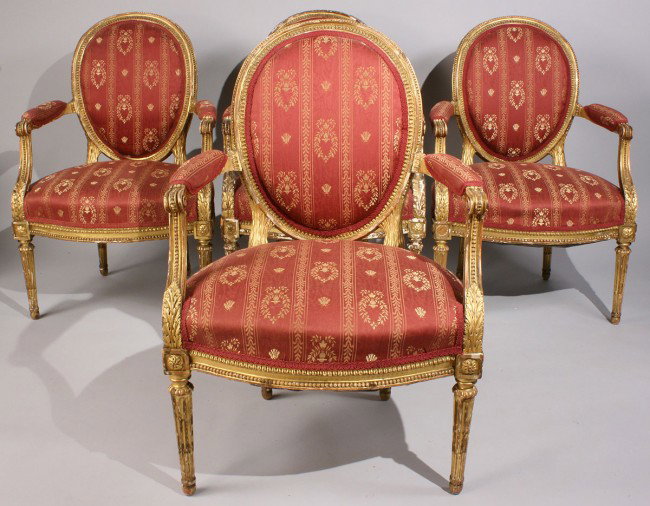 4 Louis XVI style Giltwood Armchairs: Set of four Louis XVI style fauteuils with oval upholstered backs and shaped seats, acanthus leaf and scrolled tapered arms, on tapering fluted legs headed by carved rosette. Maroon damask upholstery.