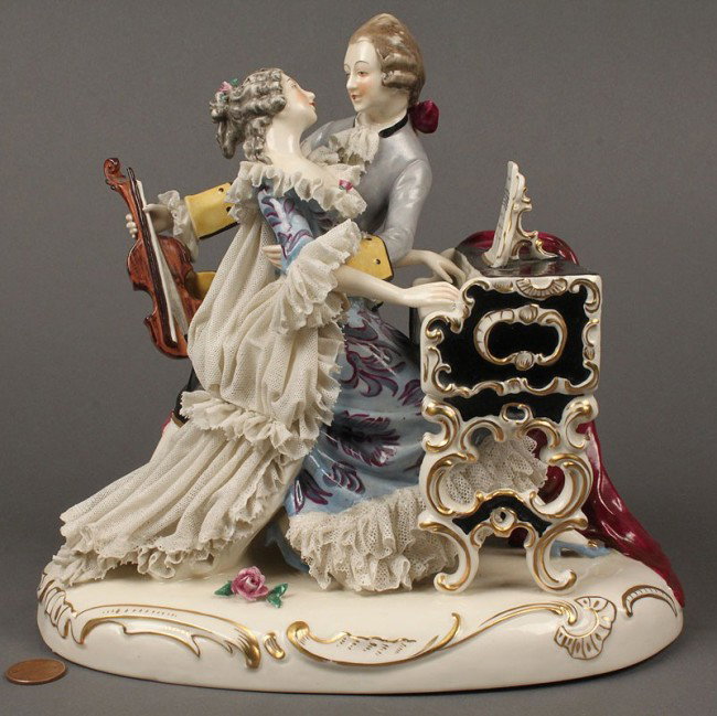 Dresden Porcelain Lace Figurine, music scene: A Dresden porcelain lace figural group, modeled as a man and woman in 18th century style dress with violin and harpsichord. Underglaze blue crown mark on side, "Germany" on base. Condition: a few tiny