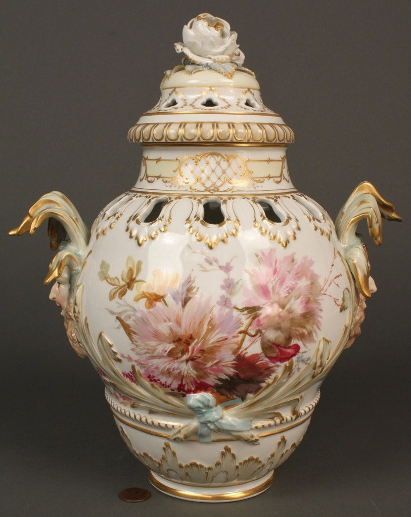 Porcelain KPM urn with lid and jester masks: Porcelain KPM potpourri urn or covered vase, the pierced cover with applied roses, the pierced vase with painted floral bouquets and foliate relief, a jester mask to each side. Base with KPM mark in r