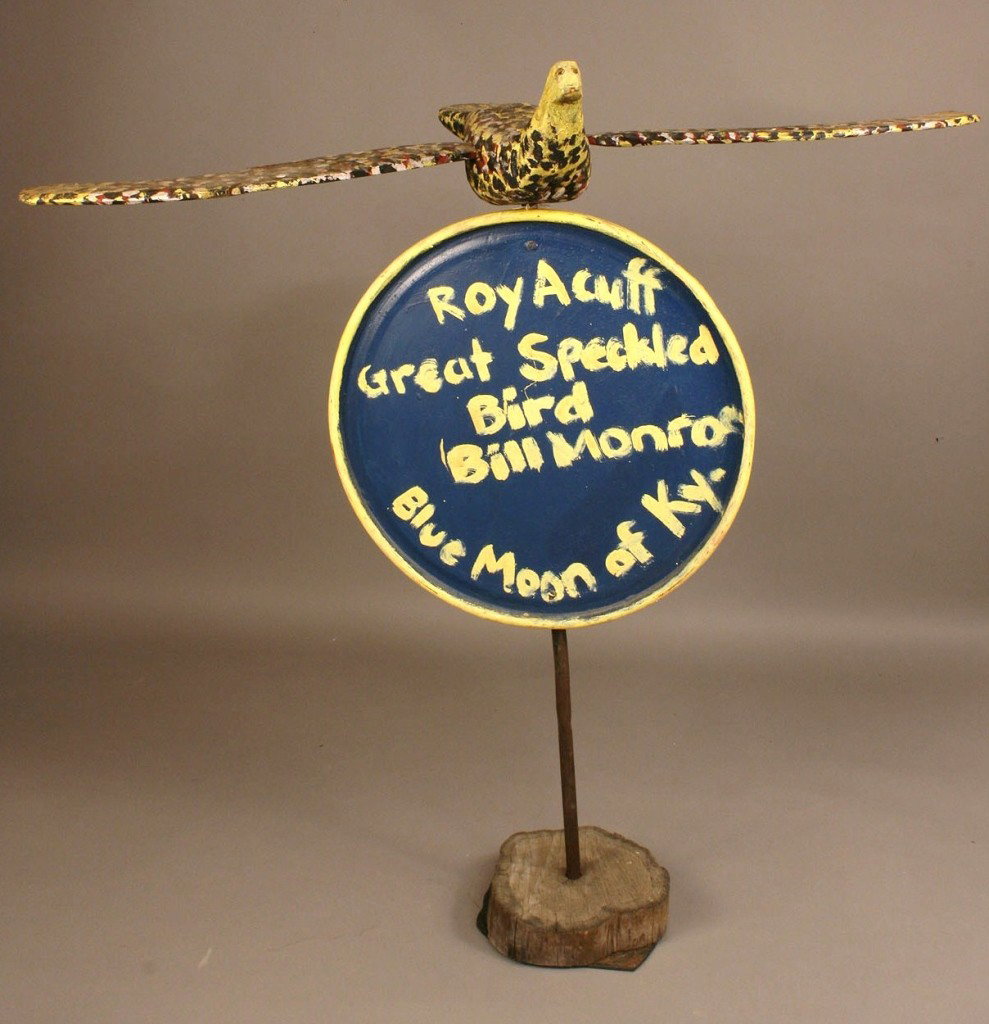 Folk art bird sculpture, tribute to Roy Acuff : Carved and painted wooden sculpture by Homer Green (Tennessee, 1910-2002) of flying bird atop a circular sign with the painted words, "Roy Acuff Great Speckled Bird / Bill Monroe of Blue Moon, Ky". Re