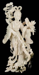 White Jade Guanyin Figure: Chinese white jade Guanyin figure, depicting the Buddhist goddess of compassion rising from waves and surrounded by vines and flowers. A black inclusion at her feet is carved in the form of lotus or