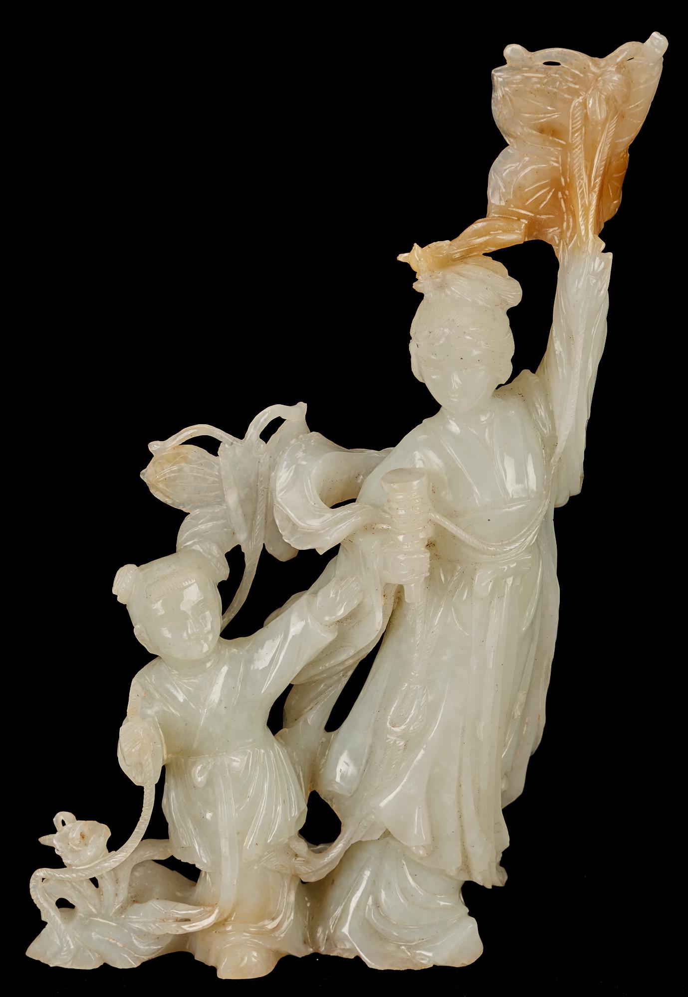 White Jade Mother & Child Figure: Chinese white jade figural group depicting a mother and child or Guanyin and child attendant, surrounded by butterflies, flowers, and vines. A russet colored inclusion forms the uppermost butterfly po