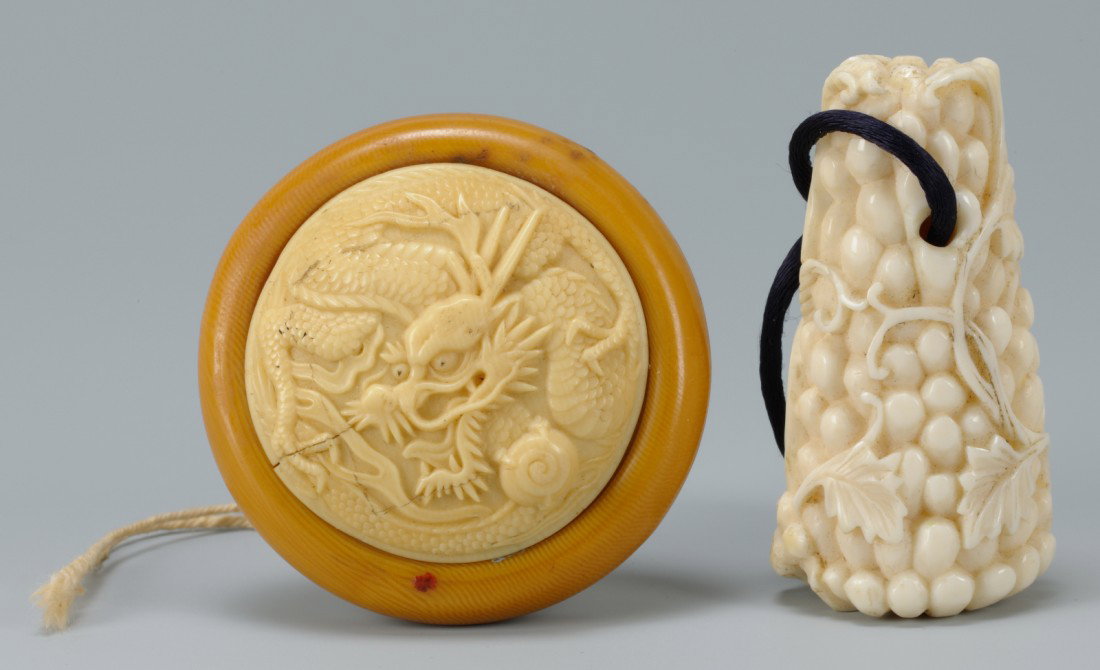 2 Carved Asian Ivory Items: Lot of 2 carved Asian ivory items. 1st item - Carved ivory netsuke, in the form of a fruit cluster with vines and cat. 2" L. 2nd item - Wooden string holder? with carved ivory top, top having carved d