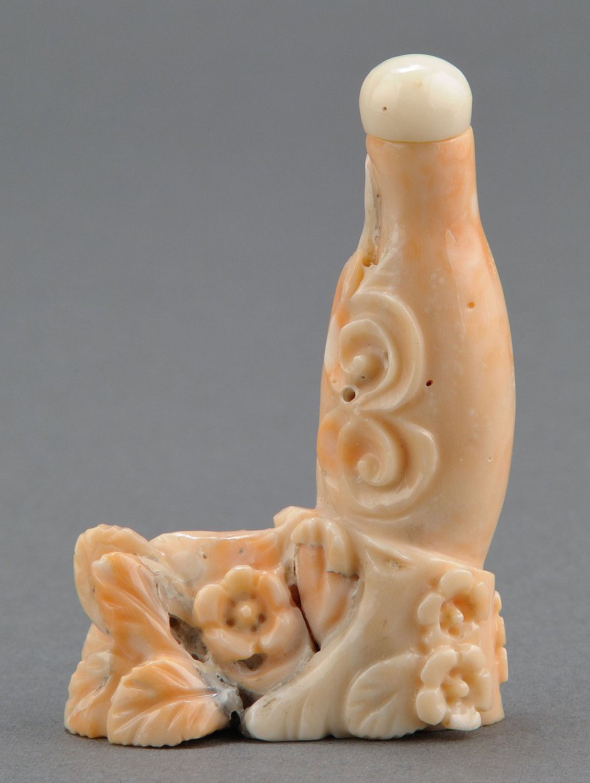 Chinese Carved Pink Coral Snuff Bottle: Chinese carved pink coral snuff bottle carved in the form of a vase resting on a pedestal of flowers. 2 3/8" H. 20th century. Provenance: From the collection of the late Fred C. Kennedy, a renowned mi