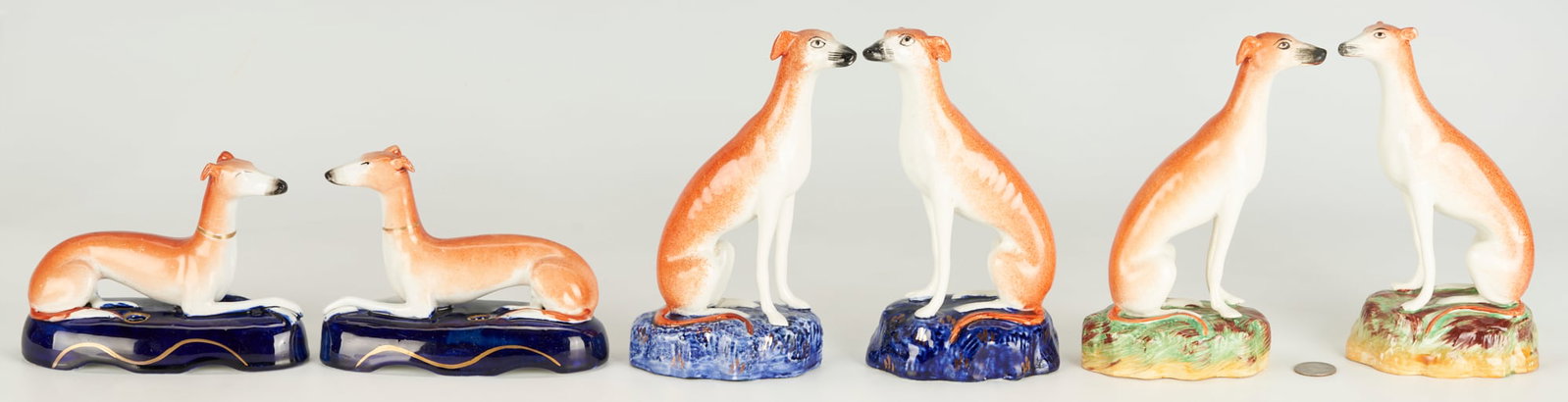 6 Staffordshire Pottery Whippets, incl. 2 Pen Holders: Grouping of English Staffordshire pottery figures including a pair of pen holder figurines in the form of recumbent, collared whippets, seated upon cobalt oval bases with gilt line detailing and two (