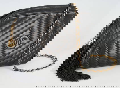 Vintage Chanel Black Quilted Lambskin Bag: Vintage Chanel black quilted chevron lambskin bag with black and interlocking "CC", side pocket, gilt chain black lambskin shoulder strap and matching tassel to zipper. Interior lined in black leather