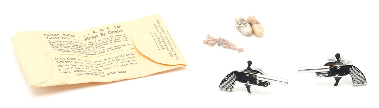 Little Atoms 2mm Pinfire Miniature Pistol Cap Gun Cufflinks: Stainless steel pistol cufflinks by Little Atoms. The cufflinks are cap guns with 32 caps. The cufflinks are marked "Japan" and measure 1 3/4" L.