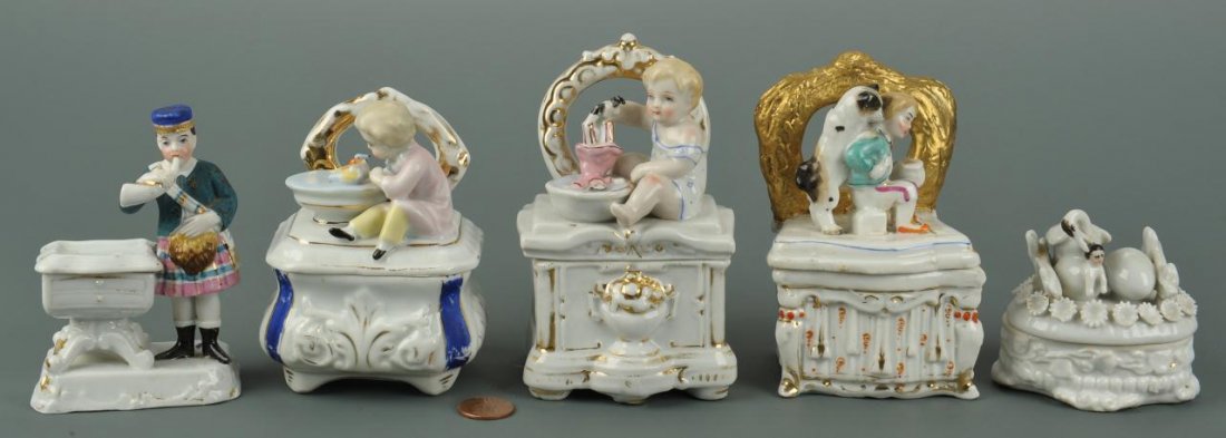 5 porcelain fairings or trinket boxes: Five Victorian or Edwardian porcelain fairings or trinket boxes including two by Conta & Boehme. 1st item: Bagpiper figure with table, whose top lifts to reveal a small box. Costume is partially ungla