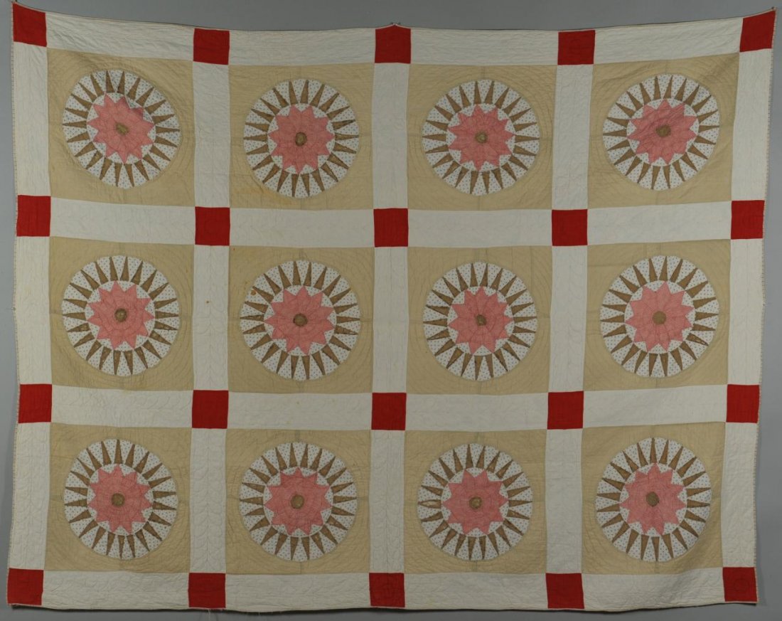 Compass star variant quilt: Pieced and appliqued quilt, Mariner's Compass or Starburst variant pattern. Twelve blocks of stars or suns, each centered by a star made from red and white patterned calico and 22 taupe-colored rays, 