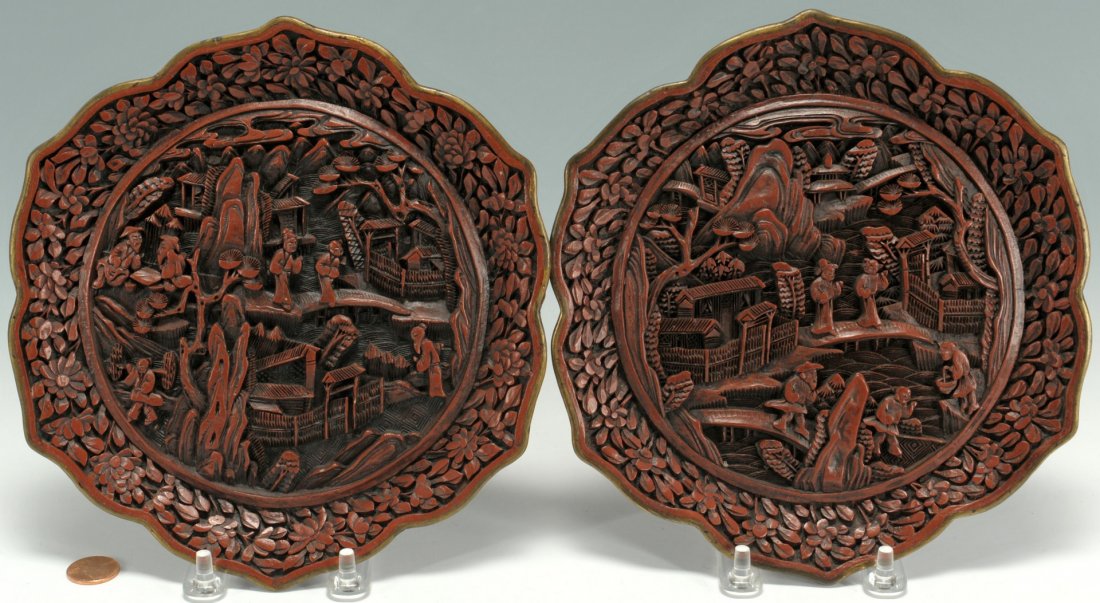 Pair of Chinese carved cinnabar lotus plates: Pair of Chinese carved cinnabar lotus design plates with scenic landscape and figure designs to front, gilt rims and seals on backs. 7-1/4" diameter. Chinese, probably early 20th century. Provenance: