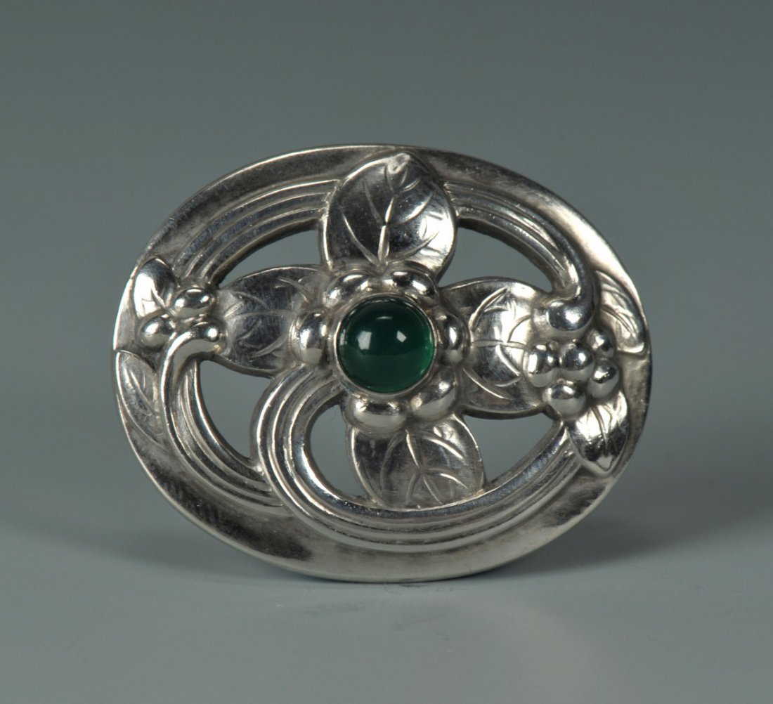 Georg Jensen Sterling Silver and Tourmaline Pin: Georg Jensen sterling silver and green tourmaline brooch, the flower leaf and vine design bezel set with a cabochon green tourmaline, 1-5/16" H x 1-5/8" W. Marked Georg Jensen Sterling Denmark 138. 0.