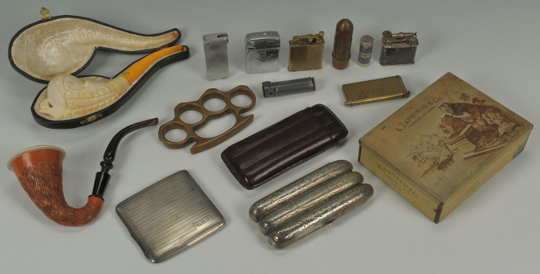 Lot of smoking related items and pr brass knuckles: A group of early 20th century smoking related items and a pair of brass knuckles. Includes 2 carved Meerschum pipes with Bakelite handles, one marked CAO in leather case, 5-7"L; an engraved silverplat