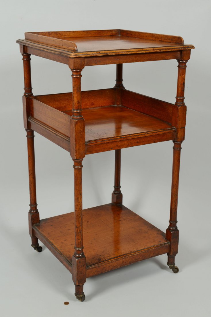 English Regency Dumb Waiter: English Regency dumb waiter or tiered stand, mahogany, with galleried top over two open shelves joined by turned posts with turned feet, raised on brass castors. Stamped underside with a crown and the