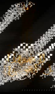 Baccarat Style Gilt Bronze 12-Light Chandelier: Baccarat style gilt bronze and cut crystal chandelier consisting of two (2) tiers of scrolled arms with twelve (12) total lights fitted with crystal bobeches and fabric shades, draped with bead garlan