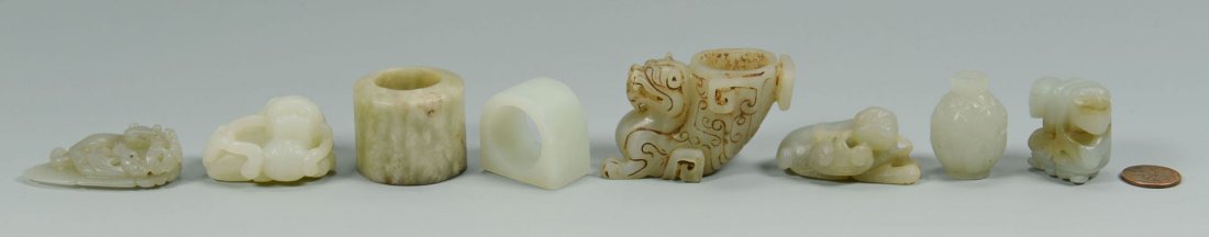 Grouping of 8 Carved Chinese Jade Articles: Grouping of eight carved Chinese jade articles including a miniature vase with carved lotus petal decoration, two archer's rings, a recumbant foo dog with ball, a recumbant foo dog incense holder, a l