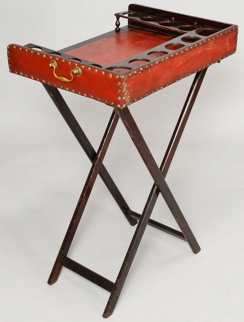 Butler's Tray on Stand: Wood and red leather butler's tray on stand, the top with cup or bottle receptacles along the perimeter, brass tacks and handles, together with a black painted wooden folding stand. Tray measures 19 1