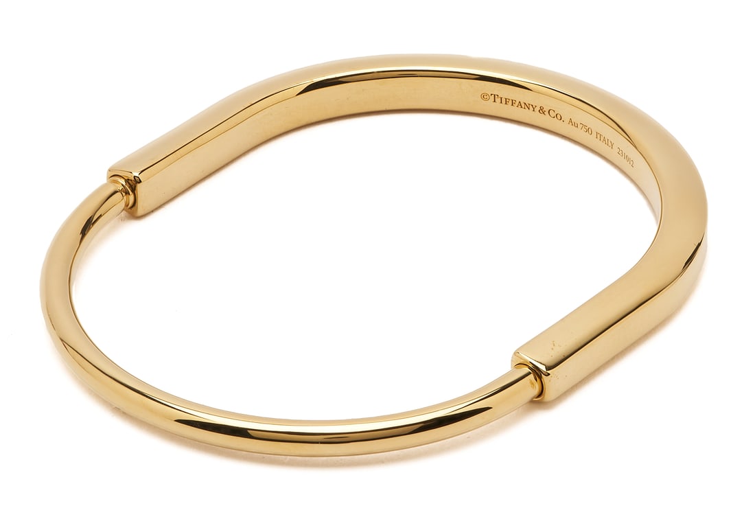Tiffany & Co 18K Gold Lock Bangle Bracelet: Ladies' 18K yellow gold lock bangle bracelet by Tiffany and Company. The bracelet is marked "Tiffany & Co. Au750 Italy 231012" and XRF tests 18K gold. The bracelet is 7 1/2 in.