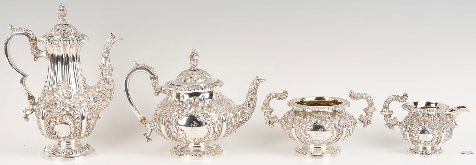 Assembled 4-Pc English Regency Sterling Tea Service: An assembled four-piece English Regency sterling silver tea service, all with fluted-shaped bodies embossed in high relief with scrolls, shells, flowers, and acanthus leaves, with acanthus capped