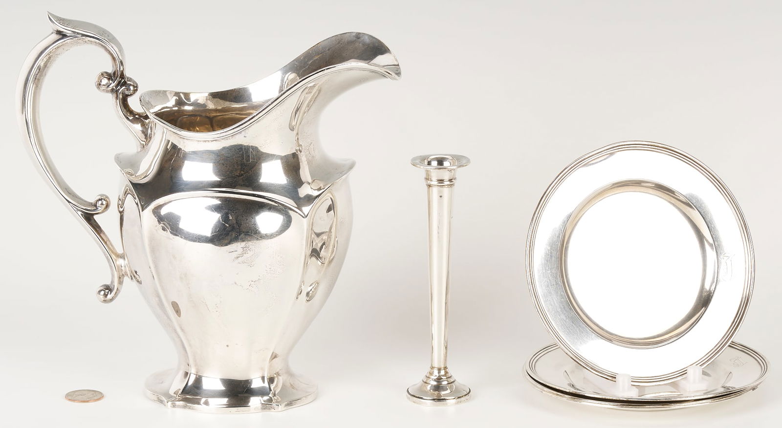 6 Sterling Silver Table Items: Grouping of six (6) sterling silver table items, including an American helmet form water pitcher with shaped sides and c scroll handles, four (4) International #H413 bread plates, and one (1) Fisher