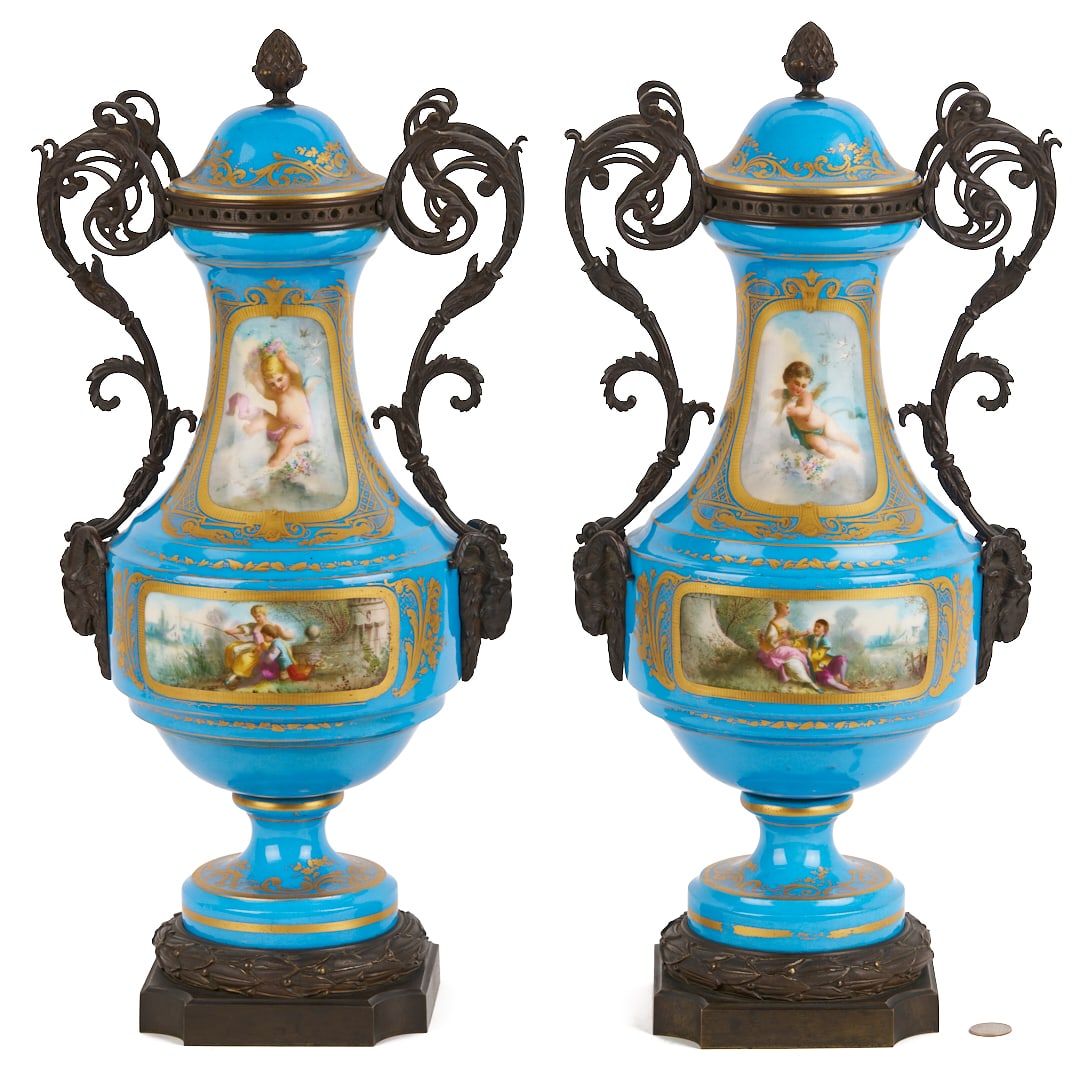 Pair of French Sevres Style Porcelain Urns: Pair of Sevres-style porcelain lidded urns having celeste blue grounds with vignettes depicting cupids, musical imagery, and courting couples in landscape settings. Gilt highlights throughout and scro