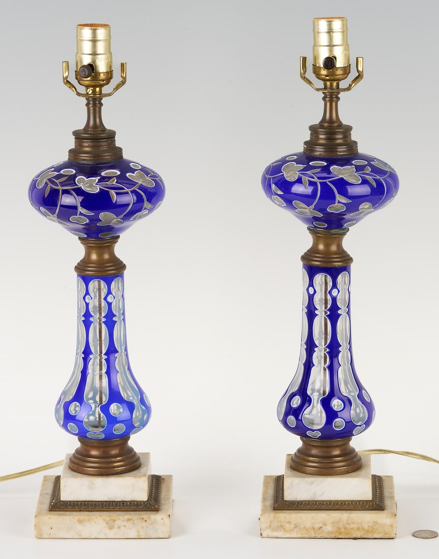 Pair of Victorian Cobalt Double Overlay Glass Lamps: Pair of Victorian cut overlay glass lamps, cobalt blue to colorless, each with pyriform font having a leafy floral design, raised on a matching baluster form pedestal with double step marble base havi
