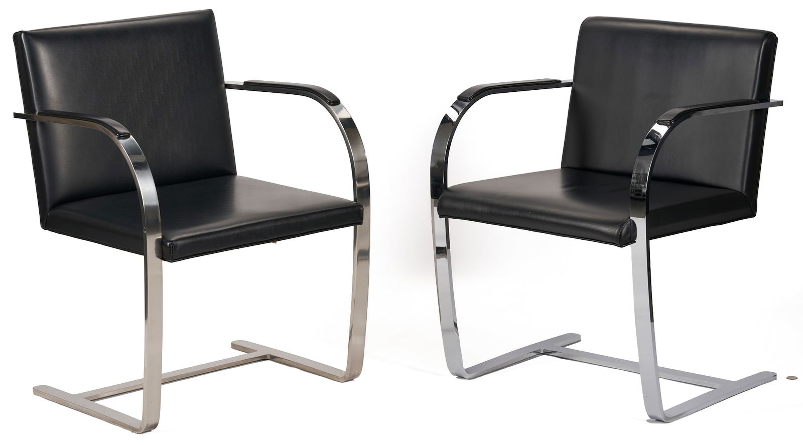 Pair of Knoll Mid-Century Brno Flat Bar Chairs: Pair of Knoll International Mid-Century Brno Flat Bar Arm Chairs, originally designed by Ludwig Mies van der Rohe in 1930. Padded black upholstery and stainless steel construction. One chair retains t