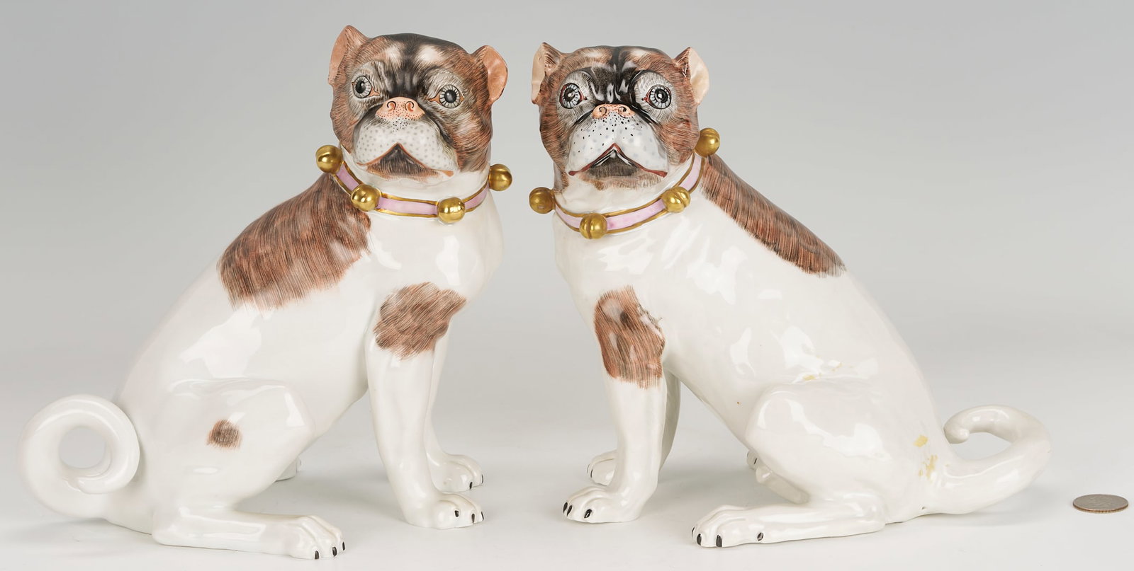 Pr. of Royal Dresden Porcelain Pug Figures: Pair of German Dresden porcelain figures of pug dogs, one male and one female, both depicted seated with painted pink collars having applied bells. Both with blue Dresden hallmark. 8 in. H x 8 3/