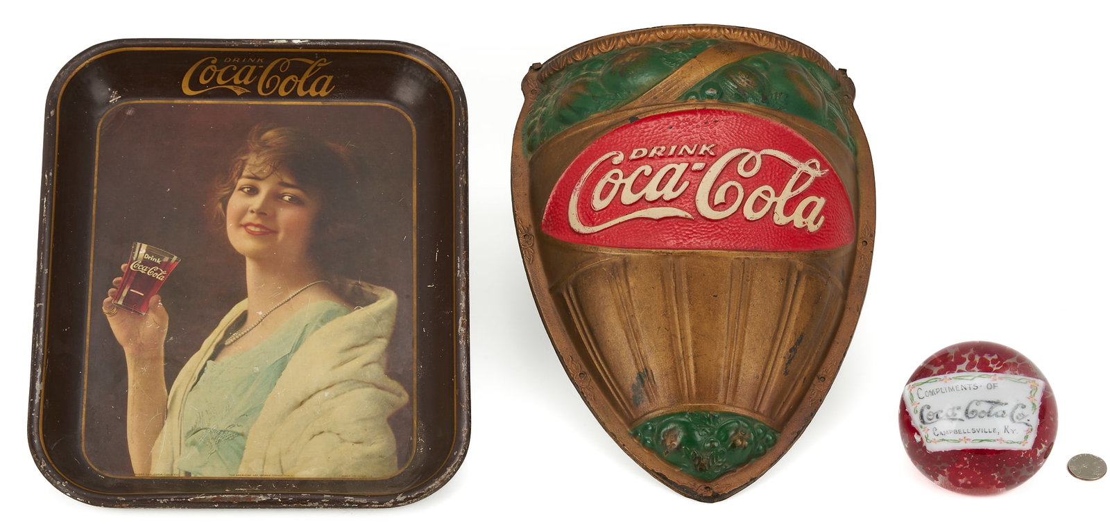 3 Coca Cola Promotional Items: Paperweight, Tray & Wall Pocket: 1st item: Coca-Cola promotional paperweight, red controlled bubbles within a clear glass body, featuring a white insert with a red and green floral border reading "Compliments of Coca-Cola Co. Ca