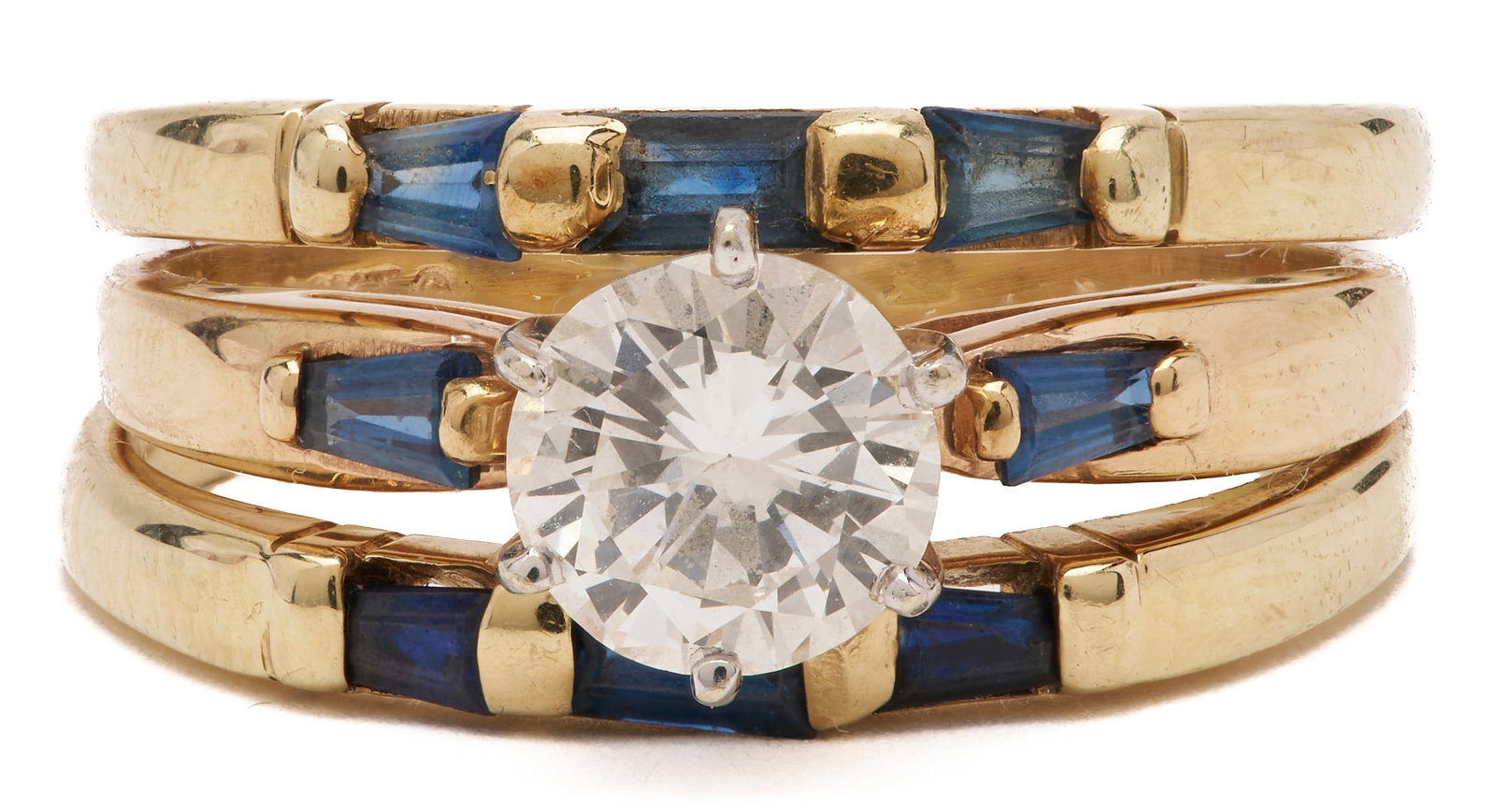14K Yellow Gold Diamond and Sapphire Ring: Three assembled 14K yellow gold bands featuring a 1.00 carat diamond, graded approximately H-I color and SI1 clarity. Accented by six natural tapered baguette-cut sapphires and two natural straight ba
