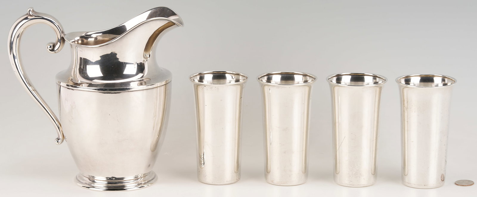 Wallace Sterling Water Pitcher w/ 4 Cups: Sterling silver pitcher and four tall sterling silver highball tumblers. Item 1: Wallace silver water pitcher, urn form with a helmet spout, c-scroll handle with spur, and a round, stepped base. Maker